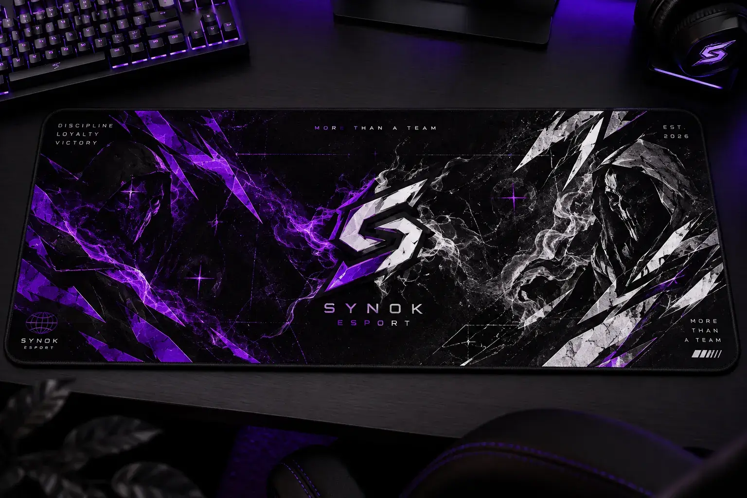 Tapis de souris Synok posé sur un bureau, entre un clavier et un casque : logo S au centre, éclats violets et blancs.